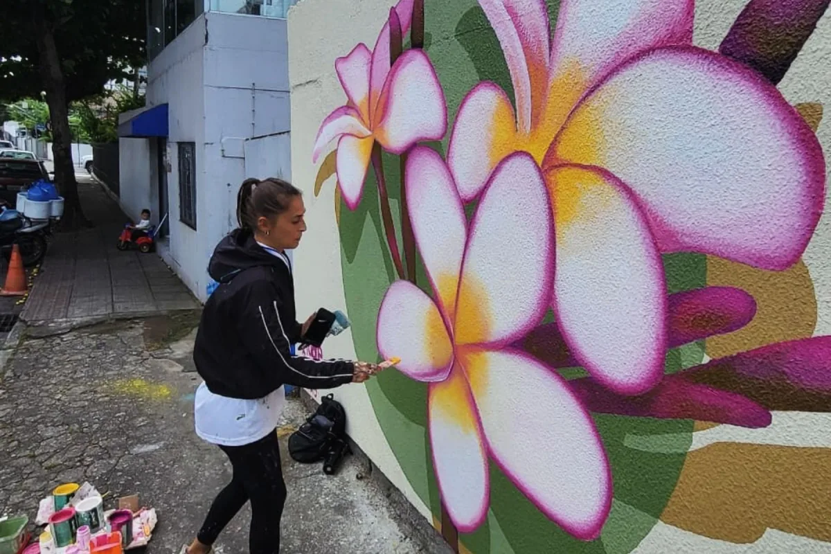 Tuane Arte pintando flores de jasmim em mural artístico