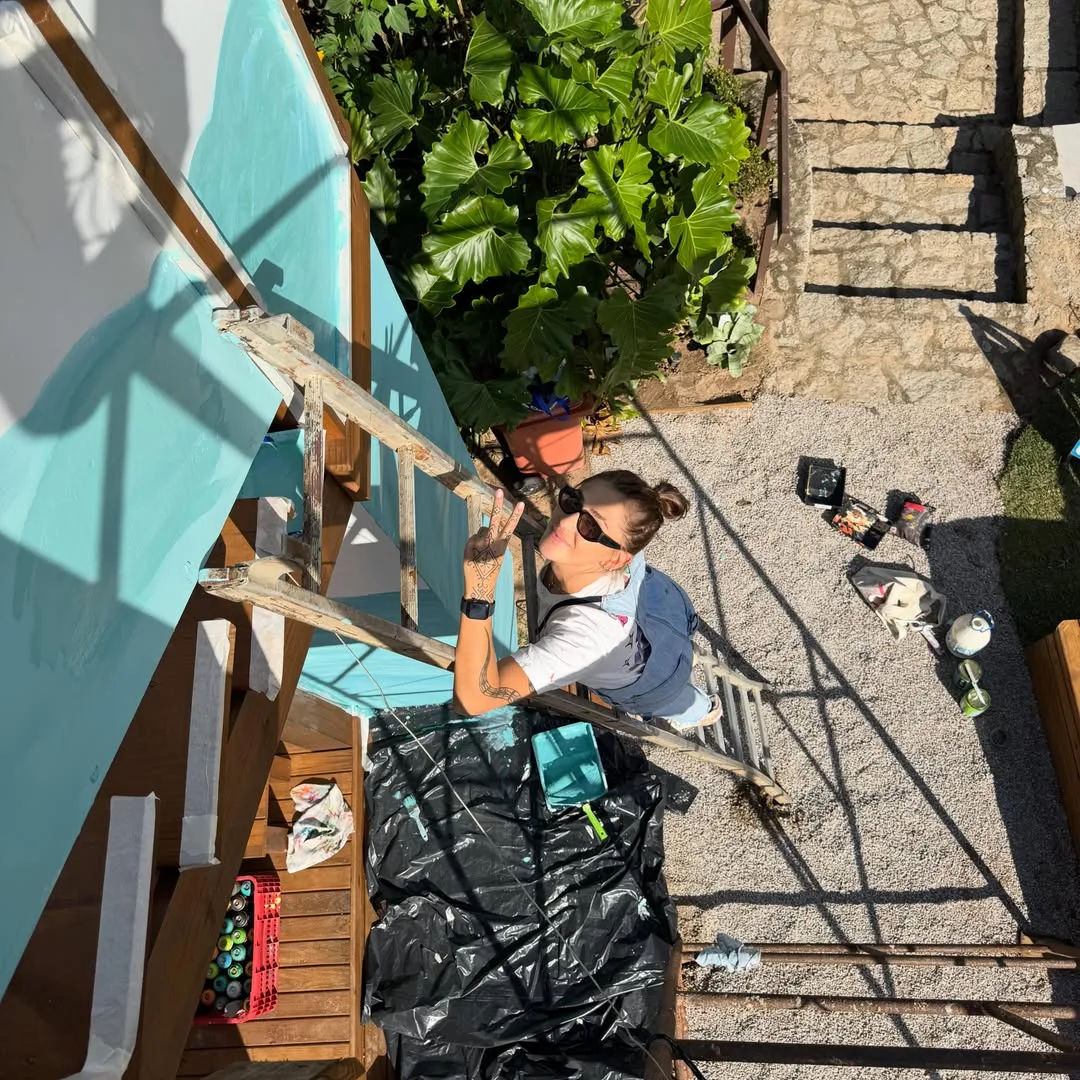 Tuane Arte durante a pintura de um mural em quintal